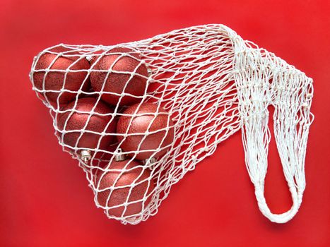 White string cotton eco bag with five christms tree balls on red background. Holiday simple flat lay. Ecology zero waste concept. Stock photo.