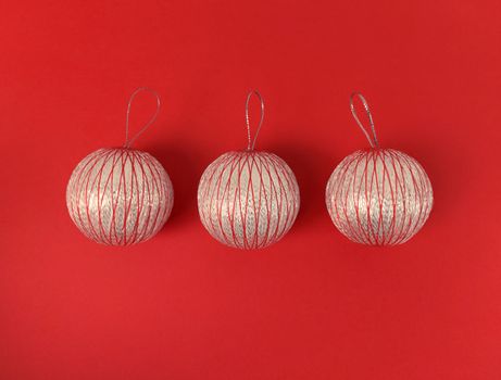 Three Christmas balls on red background. Minimalistic holiday flat lay.