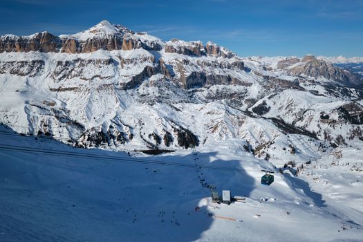View of a ski resort piste with people skiing in Dolomites in Italy with cable car ski lift. Ski area Arabba. Arabba, Italy