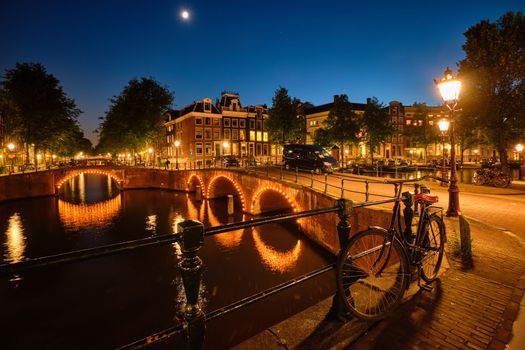 Night view of Amterdam cityscape with canal, bridge and medieval houses in the evening twilight illuminated. Amsterdam, Netherlands