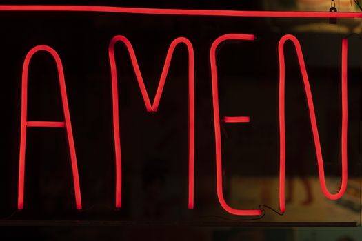 Decorative neon lights, deep red, with the word amen written.