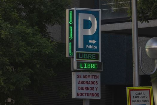 Madrid, Spain - May 18, 2020: A light, somewhat dirty sign of access to a public day and night parking lot with free space, in the Retiro district.