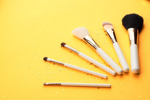 Makeup brushes with sparkles on a yellow background professional cosmetics. High quality photo