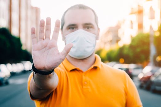 Man with a medicao mask gesturing stop.