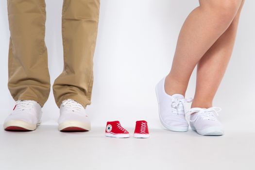 Two pairs of feet from the parents and shoes from an unborn baby, studio
