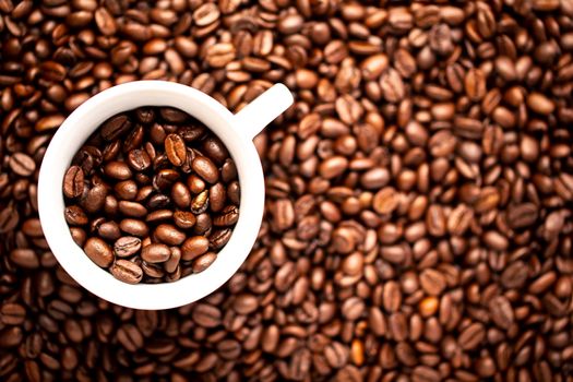 A White cup with coffee beans on a background of coffee beans