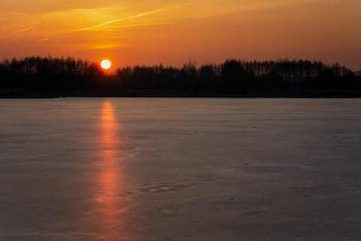 An orange sunset over a frozen lake, winter view, Stankow, Poland