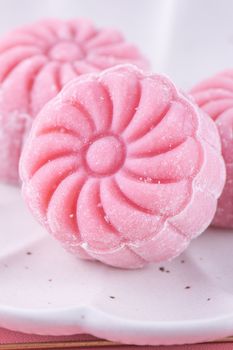 Colorful snow skin moon cake, sweet snowy mooncake, traditional savory dessert for Mid-Autumn Festival on pastel pale pink background, close up.