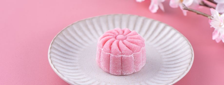 Colorful snow skin moon cake, sweet snowy mooncake, traditional savory dessert for Mid-Autumn Festival on pastel pale pink background, close up.