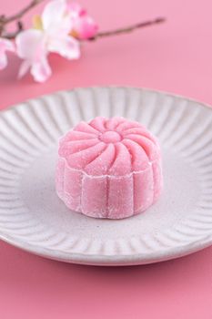 Colorful snow skin moon cake, sweet snowy mooncake, traditional savory dessert for Mid-Autumn Festival on pastel pale pink background, close up.