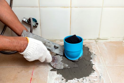 Construction workers are using plastering tools around the PVC pipe to drain the waste inside the bathroom.