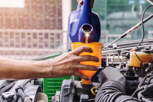 Car mechanic is adding oil to the engine, Automotive industry and garage concepts.