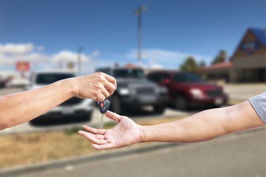 Closeup a man's hand is delivering a car key to another man's hand, use for the concept of car repair industry, insurance or automobile trading.