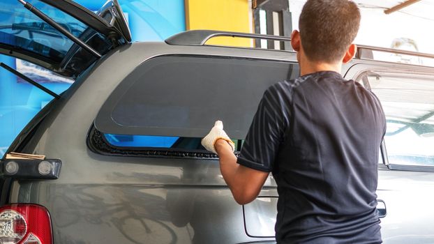 Technicians are installing automotive glass right rear of the car.