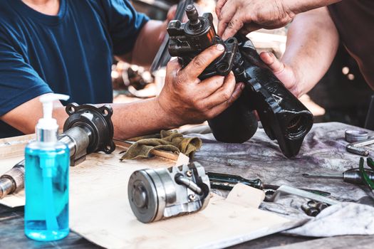 Technicians are helping to assemble the car power steering gearbox.