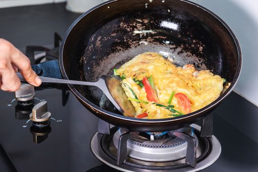 Frying eggs in a frying pan with heat from a gas stove fire in the kitchen.