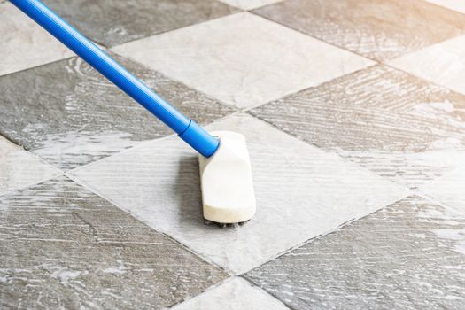 Cleaning the tile floor with floor scrubber brush.