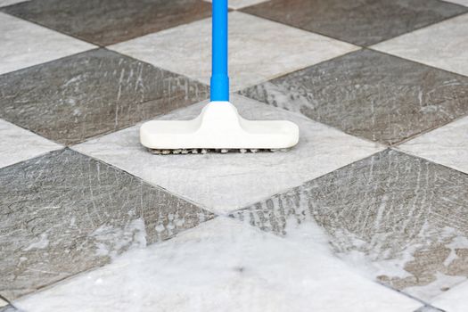 Cleaning the tile floor with floor scrubber brush.