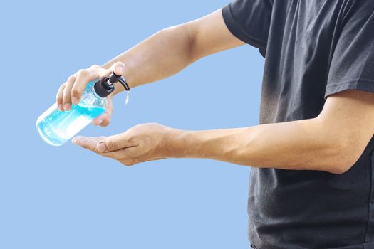 The man is cleaning his hands with alcohol gel to prevent Corona virus Covid-19 infection, isolated on blue pastel background.
