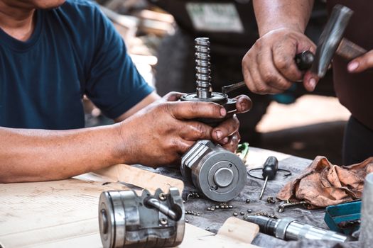 Technicians are helping to assemble the car power steering gearbox.