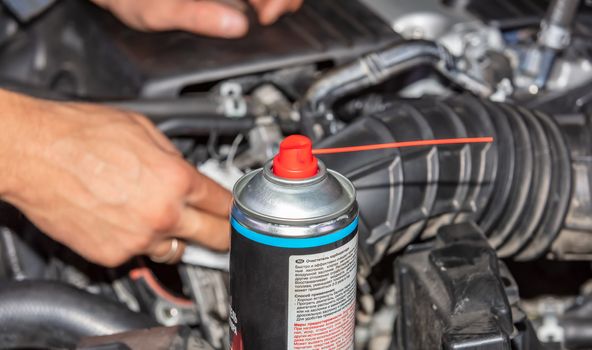 Repairman Working and fixing car engine at service shop. Mechanic man hands repair and overhaul car engine. Can with a special pressurized liquid next his hand. Hands out of focus.