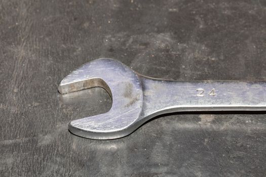 Close-up of old chrome wrench on a dirty table in repair shop