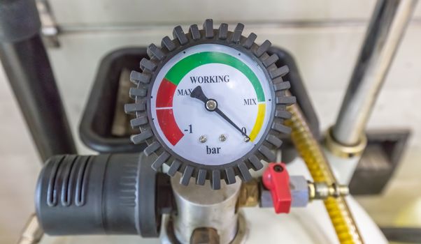 Pressure gauge Meter installed, Measuring Tool equipment close up in a car repair shop. Valve and other parts in the background are out of focus.