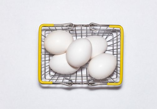 Fresh eggs in a shopping basket. Top view. Shopping, purchasing, and food delivery concept. White background. Close up shot. Isolated.