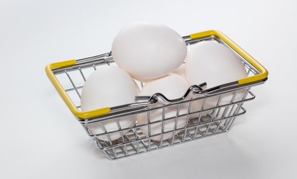 Fresh eggs in a shopping basket. Basket is completely full. High angle shot. Basket hands down. Shopping, purchasing, and food delivery concept. White background. Close up shot. Isolated.