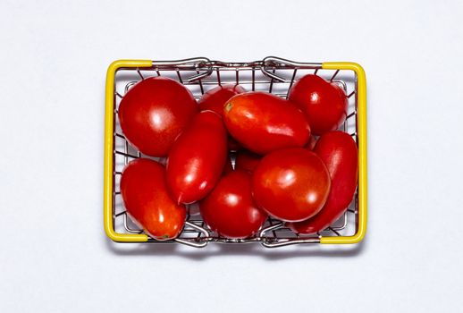Shot of tomatoes in shopping basket isolated on white background. Ripe tasty red tomatos in shopping basket. Top view. Tomato trading concept. Online shopping concept.
