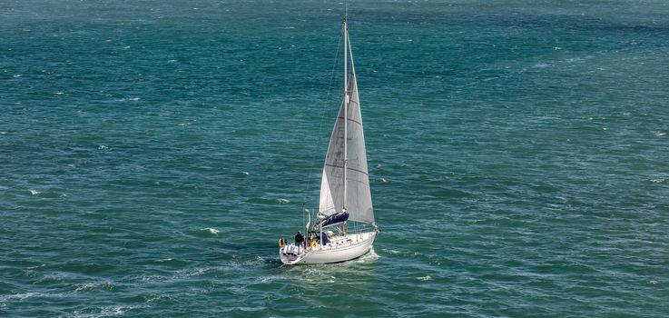 High angle shot of a white sailboat sailing in Weymouth Bay, UK. Sport and recreation concept.