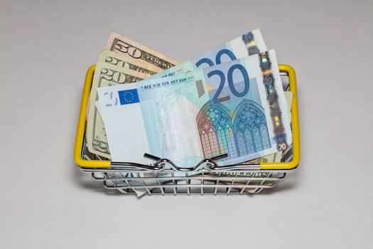Dollar and euro bills mixed up in a basket for buyers on a white background. Isolated. High angle view.