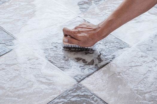 Men's hands are used to convert polishing cleaning on the tile floor.