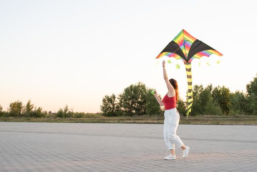 Active lifestyle. Happiness concept. Happy young woman running with a kite in a park at sunset