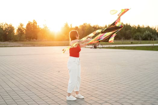 Active lifestyle. Happiness concept. Happy young woman running with a kite in a park at sunset