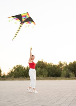 Active lifestyle. Happiness concept. Happy young woman running with a kite in a park at sunset