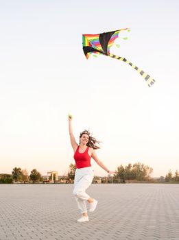 Active lifestyle. Happiness concept. Happy young woman running with a kite in a park at sunset