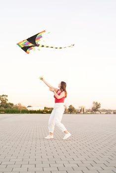 Active lifestyle. Happiness concept. Happy young woman running with a kite in a park at sunset