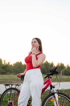 Teenage girl standing next to her bike listening to the music in the park