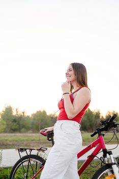 Teenage girl standing next to her bike listening to the music in the park