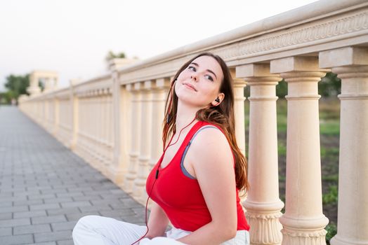 Active lifestyle. Young woman or student girl with headphones listening to music relaxing or learning language outdoors in park