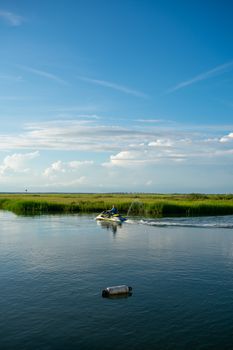 A Man on a Yellow Jetski Riding Through the Bay With Gorgeous Greenery and a Blue Sky Behind Him