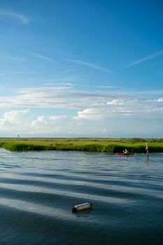 Women on a Kayak and a Canoe Slowly Riding Through the Bay With Gorgeous Greenery and a Clear Blue Sy Behind Them