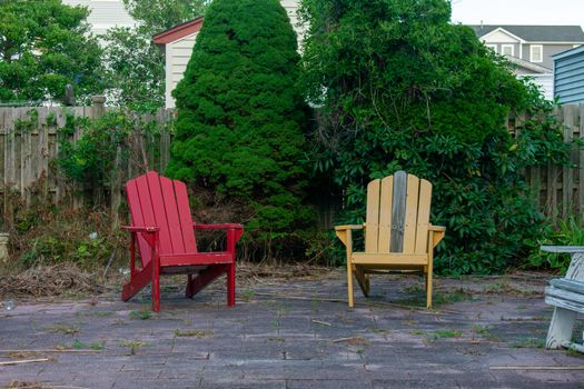 An Old Red and Yellow Lounge Chair in a Paved Backyard in a Beach Town