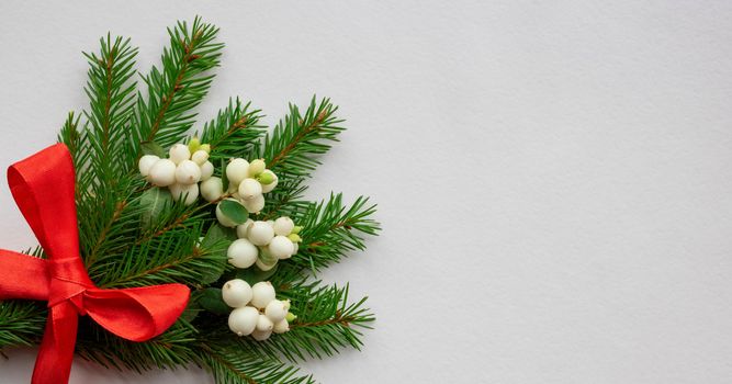 Christmas bouquet with fir branches, red bow and white dogwood berries on a white background . Christmas card. The theme of a winter holiday. Happy New Year.