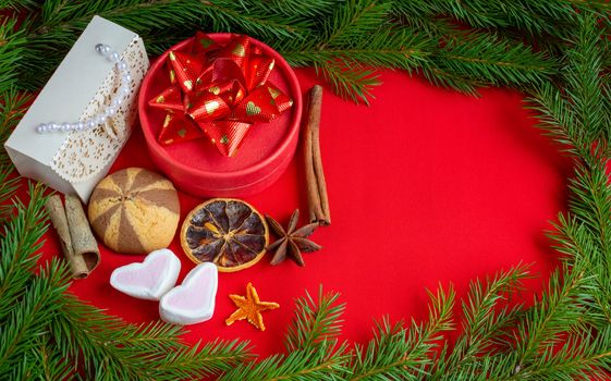 Christmas gifts lie on the background of a spruce branch on a red background. Copy of the space, banner.