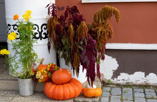 Orange pumpkins of various sizes lie on the porch of the house.The Concept Of Halloween.