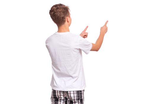 Back view. Teen boy pointing finger away at copyspace, isolated on white background. Teenager pointing fingers at something - rear view. Child in white t-shirt.