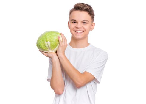 Portrait of handsome young teen boy holding fresh green cabbage and looking at camera, isolated on white background. Smiling child with healthy vegetables.