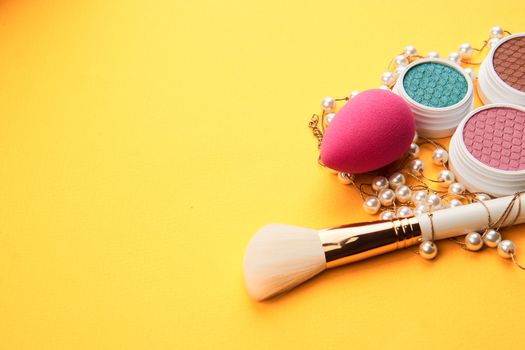 Pink makeup sponge and powder brush yellow background he cropped view. High quality photo